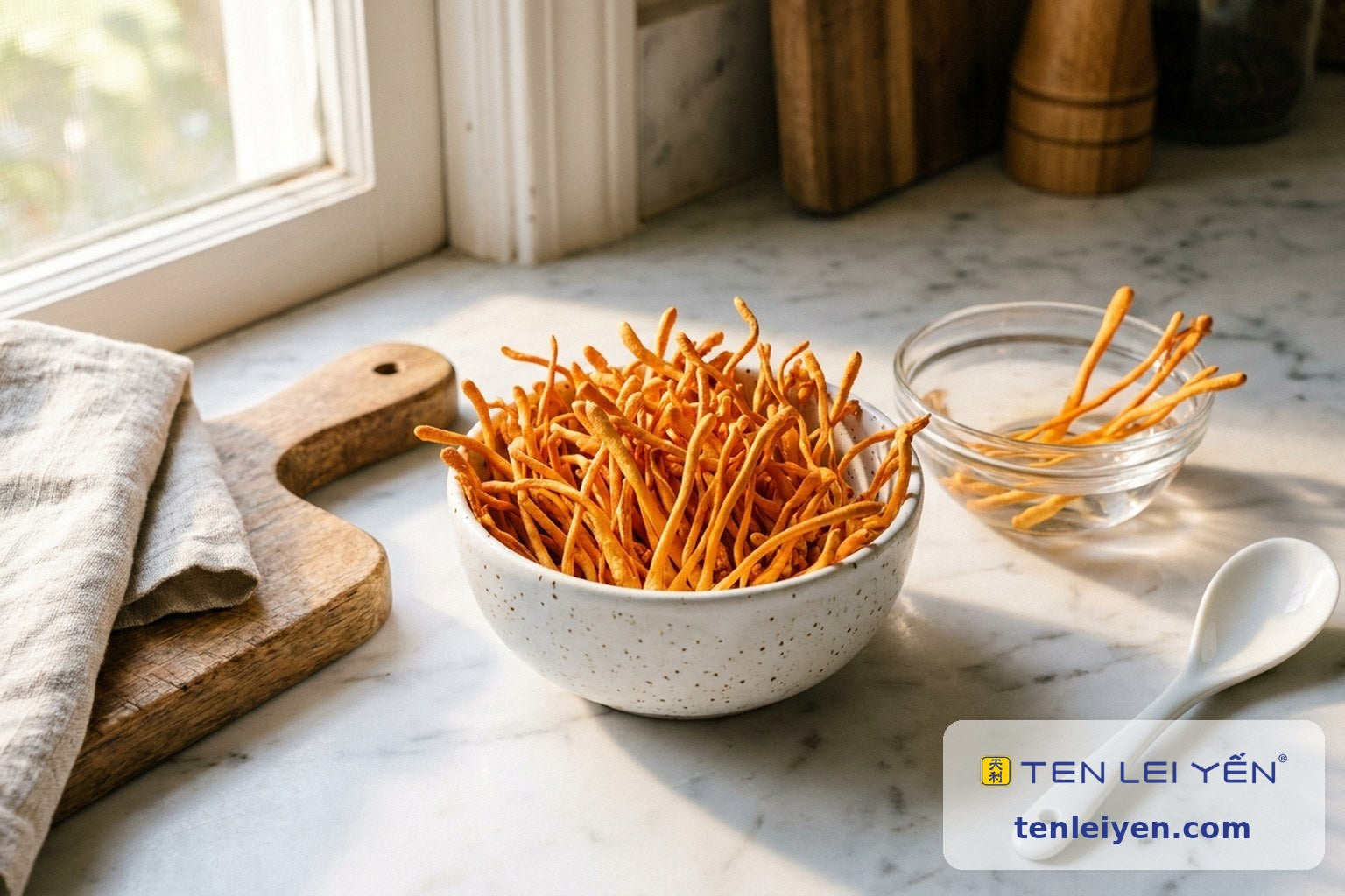 Dried Cordyceps militaris stalks in a speckled white ceramic bowl beside a small bowl soaking in water