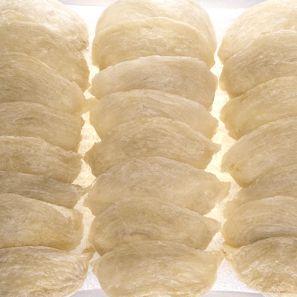 Rows of whole dried white edible bird's nests showing their natural cup shape and fine fibrous strands — Ten Lei Yen Blue Label Supreme