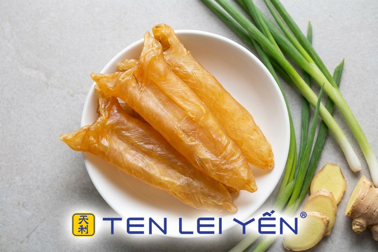 Golden-amber dried fish maw pieces on a plate beside fresh ginger and scallion, ready for deodorizing before cooking