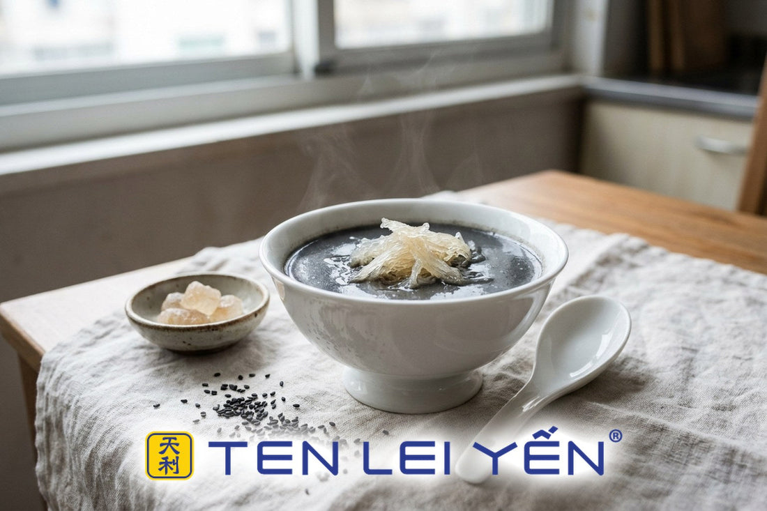 A warm bowl of black sesame sweet soup topped with fine translucent strands of edible bird's nest, white porcelain bowl and spoon