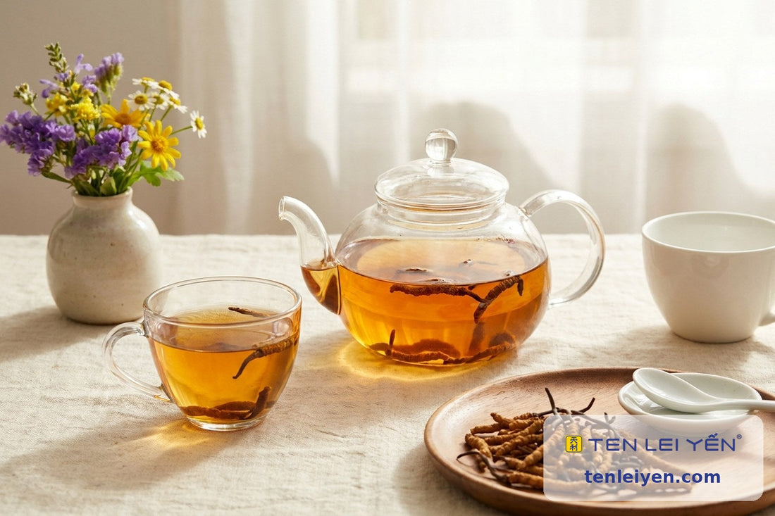 Glass teapot and cup of cordyceps tea with whole wild cordyceps steeping beside a white porcelain spoon, summer table spread