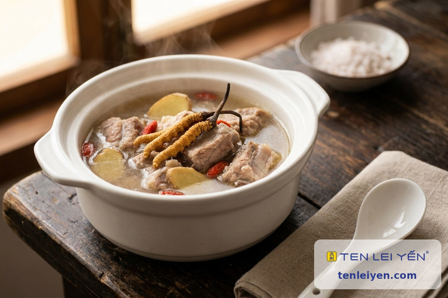 Rustic pot of pork-bone soup with two whole wild cordyceps, ginger, and goji berries beside a white porcelain spoon