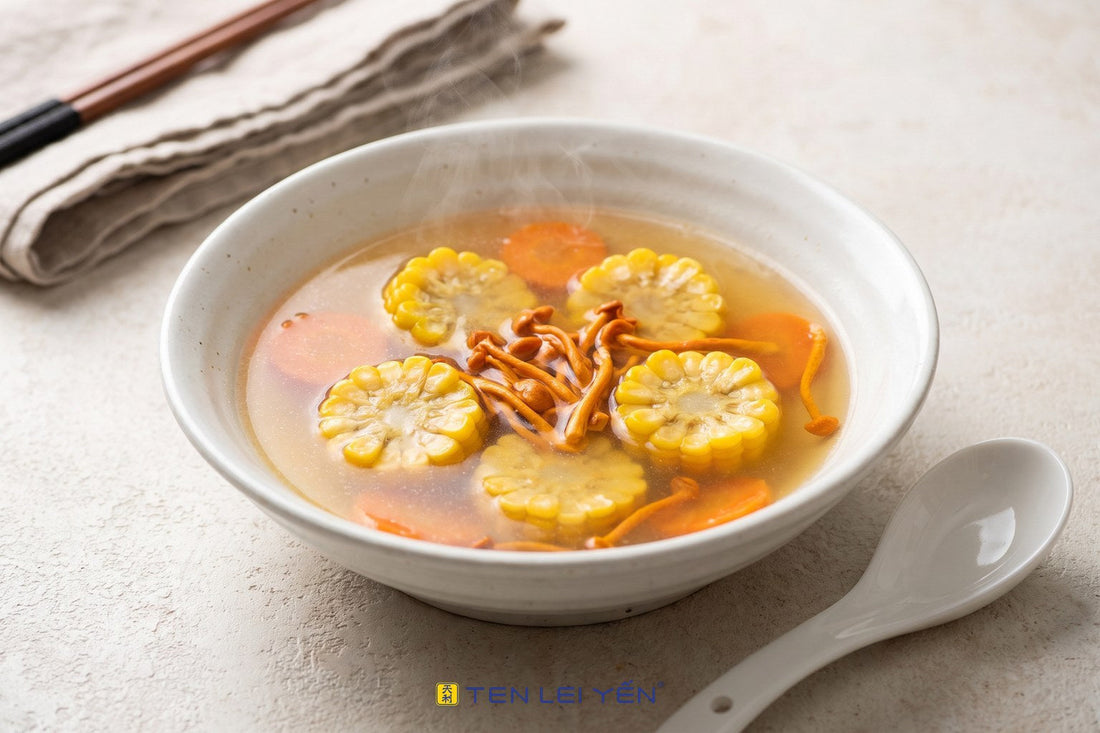 A light cordyceps and sweet corn soup with carrot rounds in a white porcelain bowl