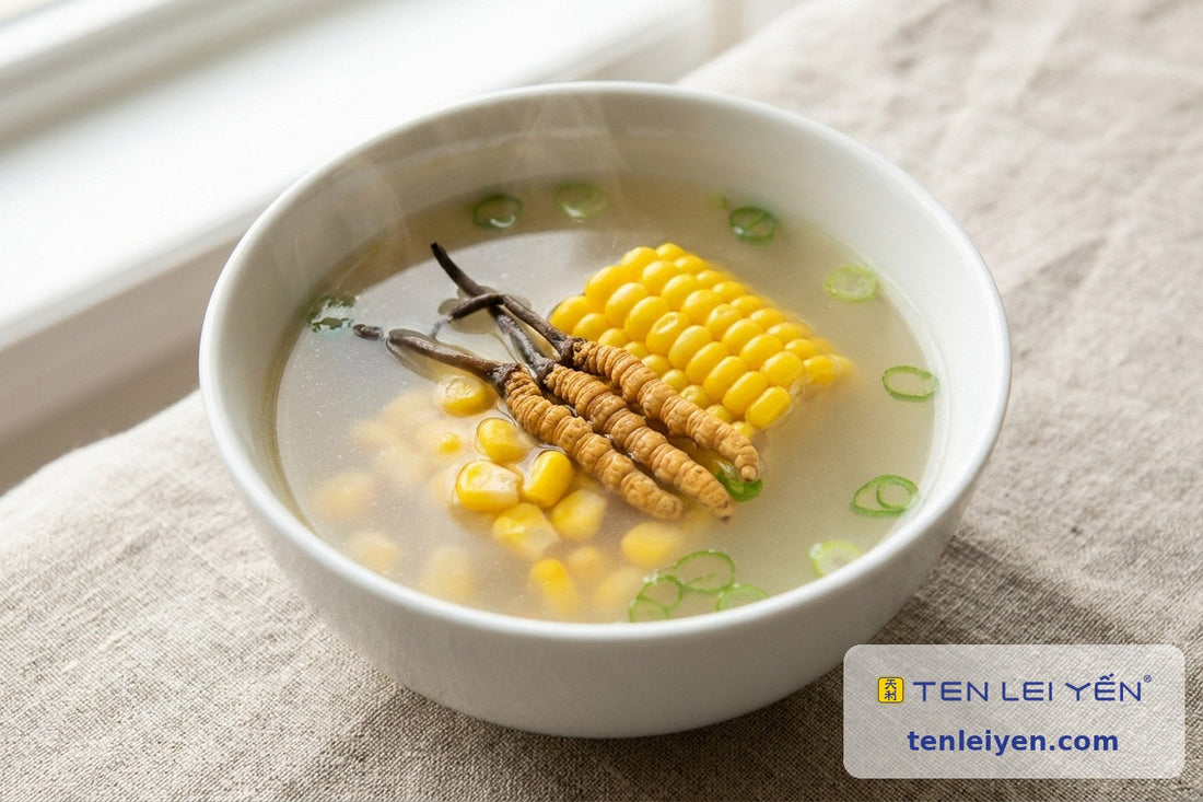 White bowl of clear cordyceps and sweet corn soup with corn cob, scallion, and whole cordyceps