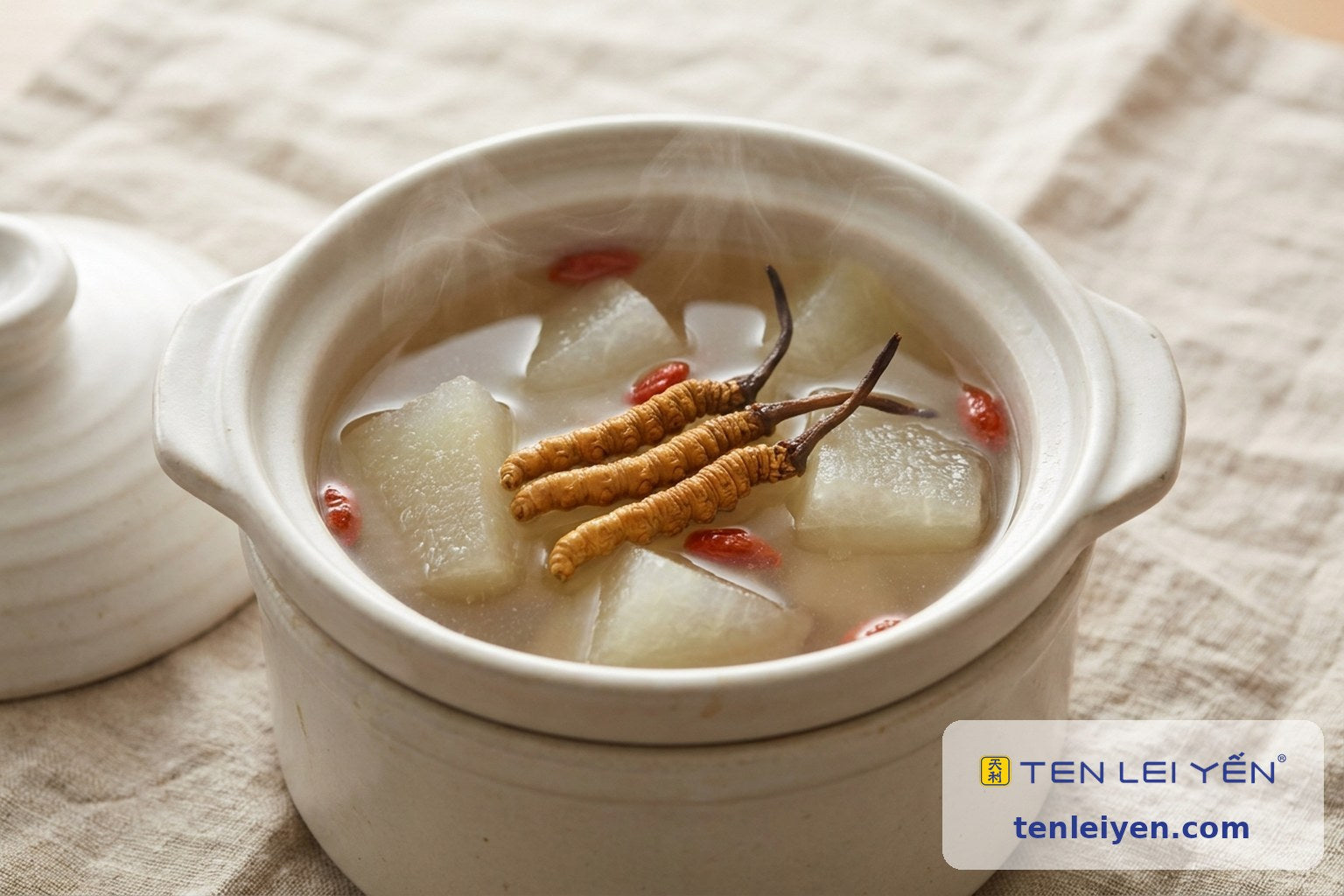 Open double-boiling pot of clear broth with winter melon chunks and whole wild cordyceps resting on top with goji berries