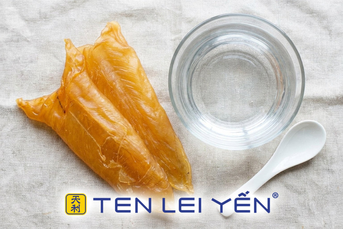 Dried golden-amber fish maw blades resting beside a clear glass bowl of water with a white porcelain spoon