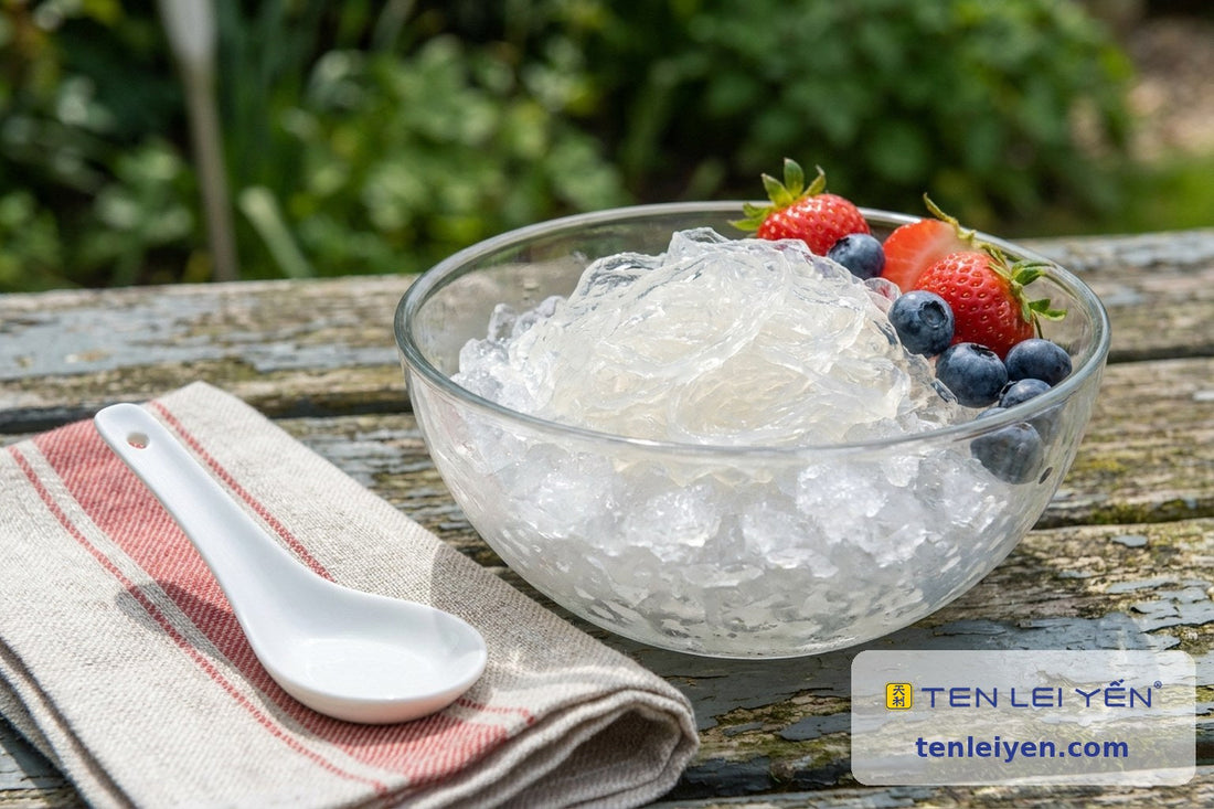 Chilled bird's nest in a glass bowl topped with fresh strawberries and blueberries beside a white porcelain spoon, picnic setting